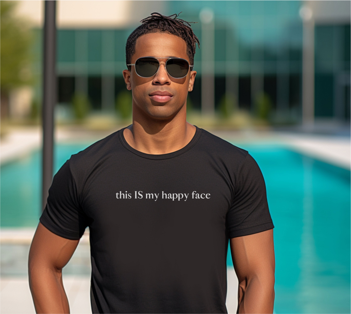 A black unisex cotton t-shirt with the text 'this IS my happy face' printed in white across the chest. All characters are lower case except the word 'IS' which are in capital letters.